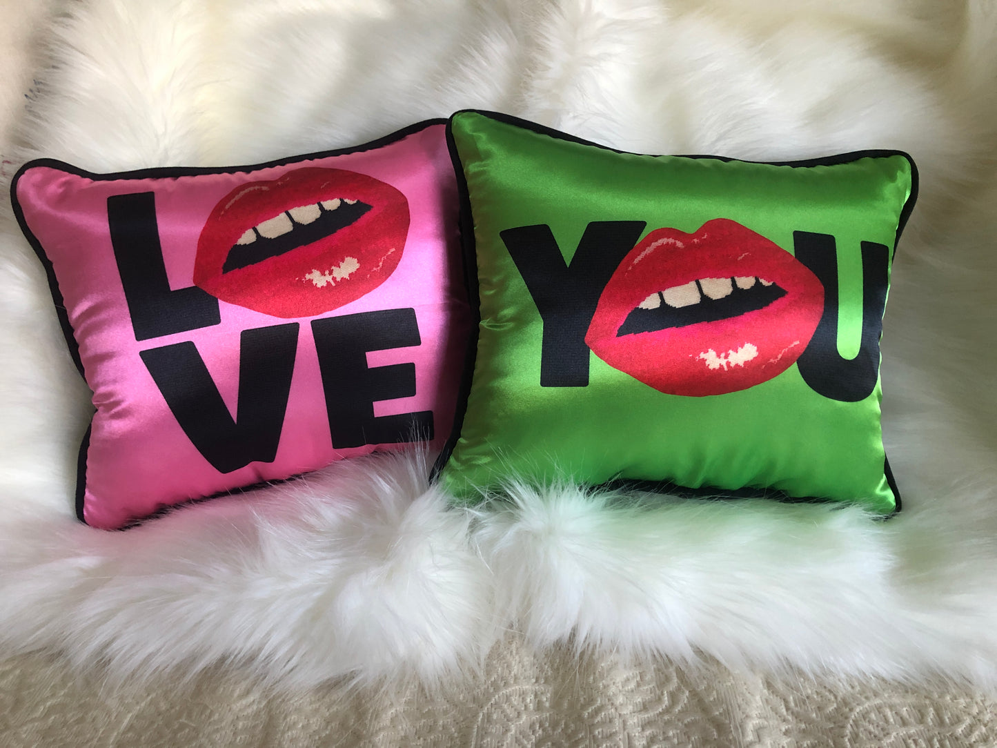 hot pink pillow with blackletters - L, red lips for an O, V & E stacked underneath & green pillow saying Y (lips) U