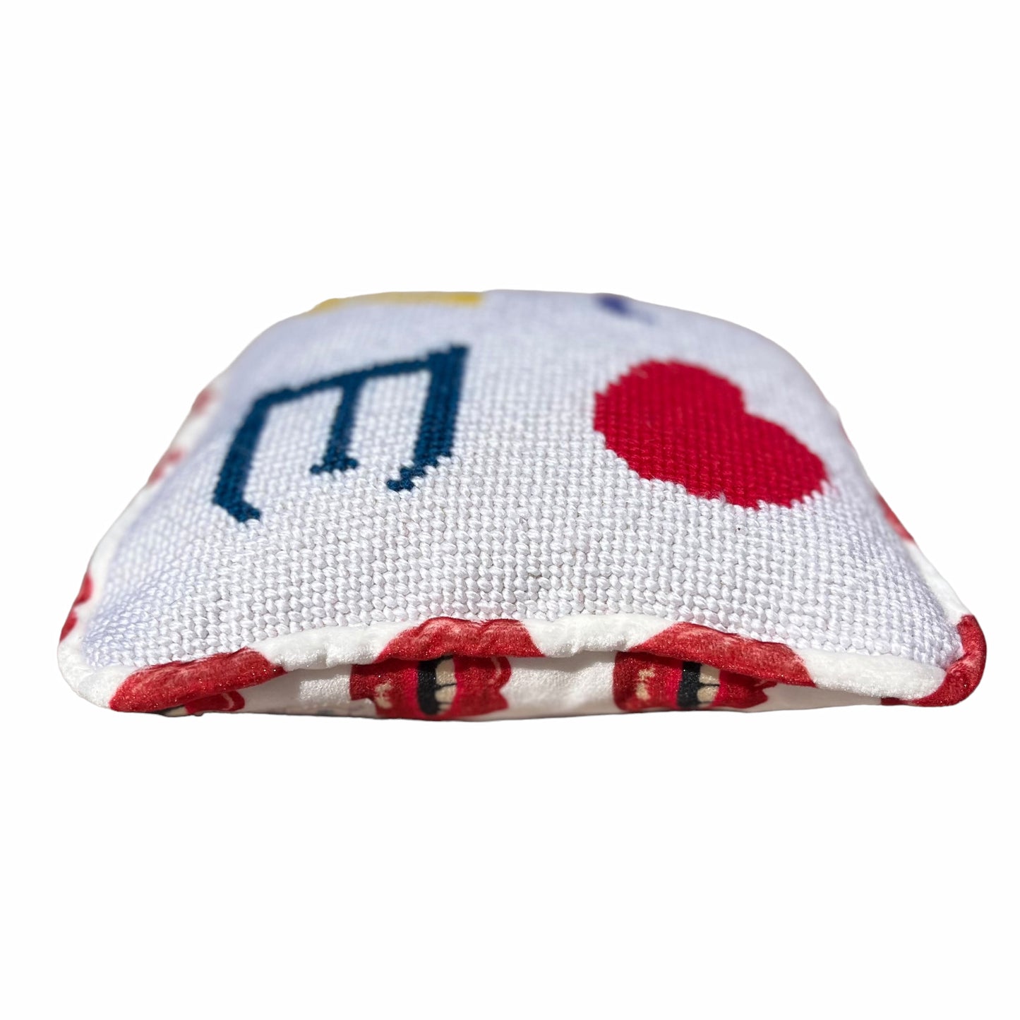 needlepoint with white background, purple L, red heart, yellow V under the L and blue E, finished in white velvet with red lips pattern