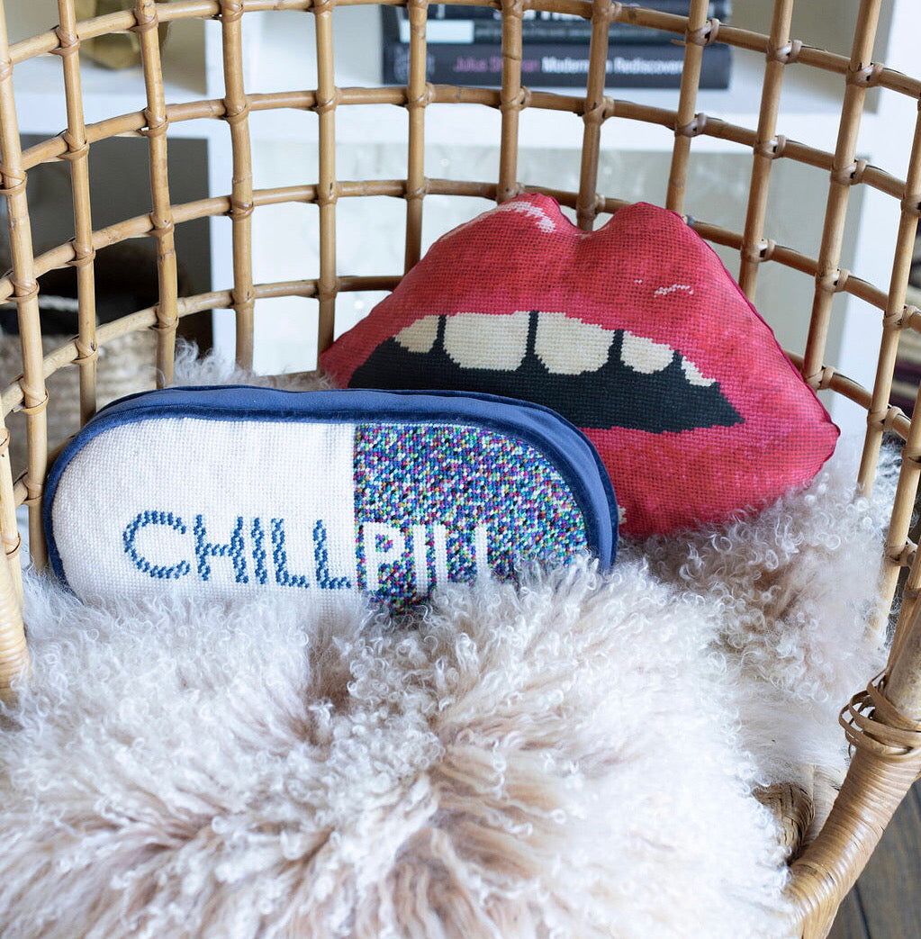 sculpted pill shape pillow is one-half white with blue letters and one half dotted, colorful pattern with PILL written in white