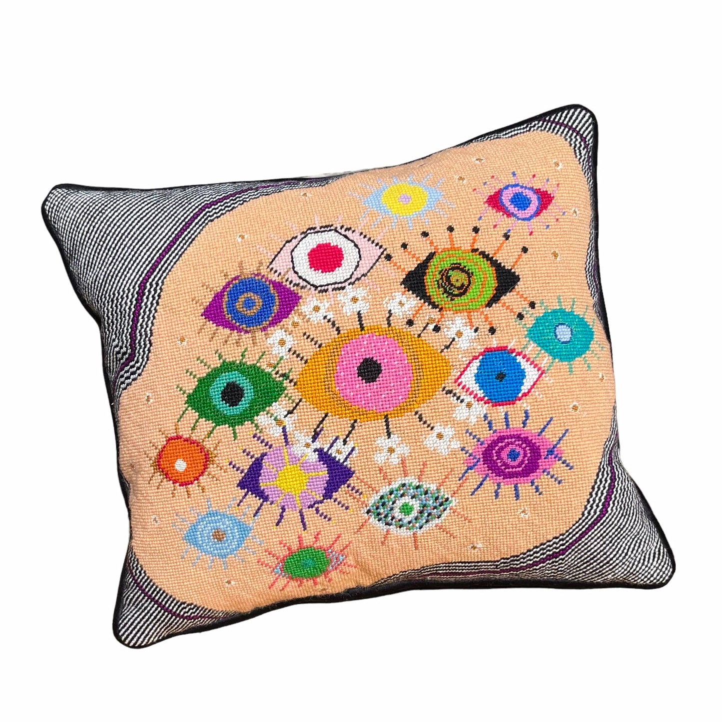 hand-embroidered lyrical pillow is covered in whimsical eyes of varying colors; vertigo band white swirl border