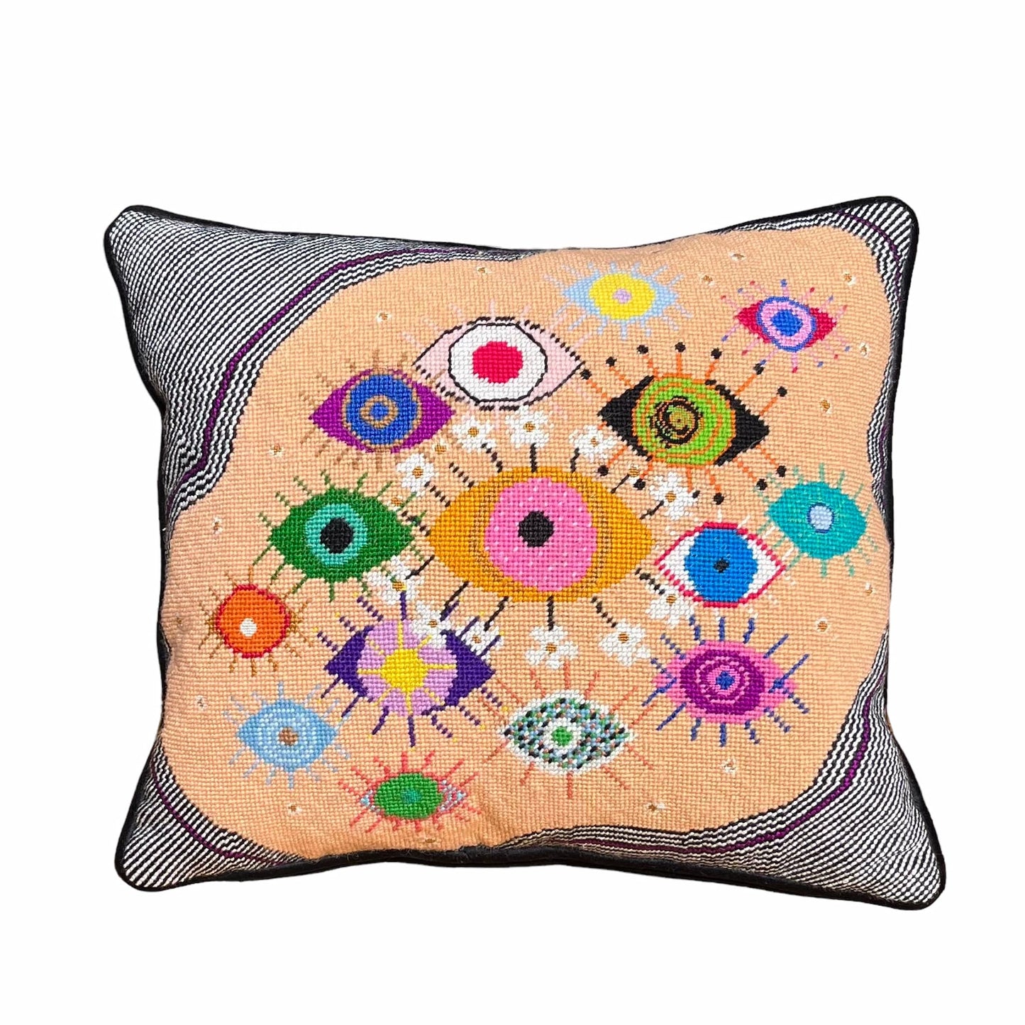 hand-embroidered lyrical pillow is covered in whimsical eyes of varying colors; vertigo band white swirl border