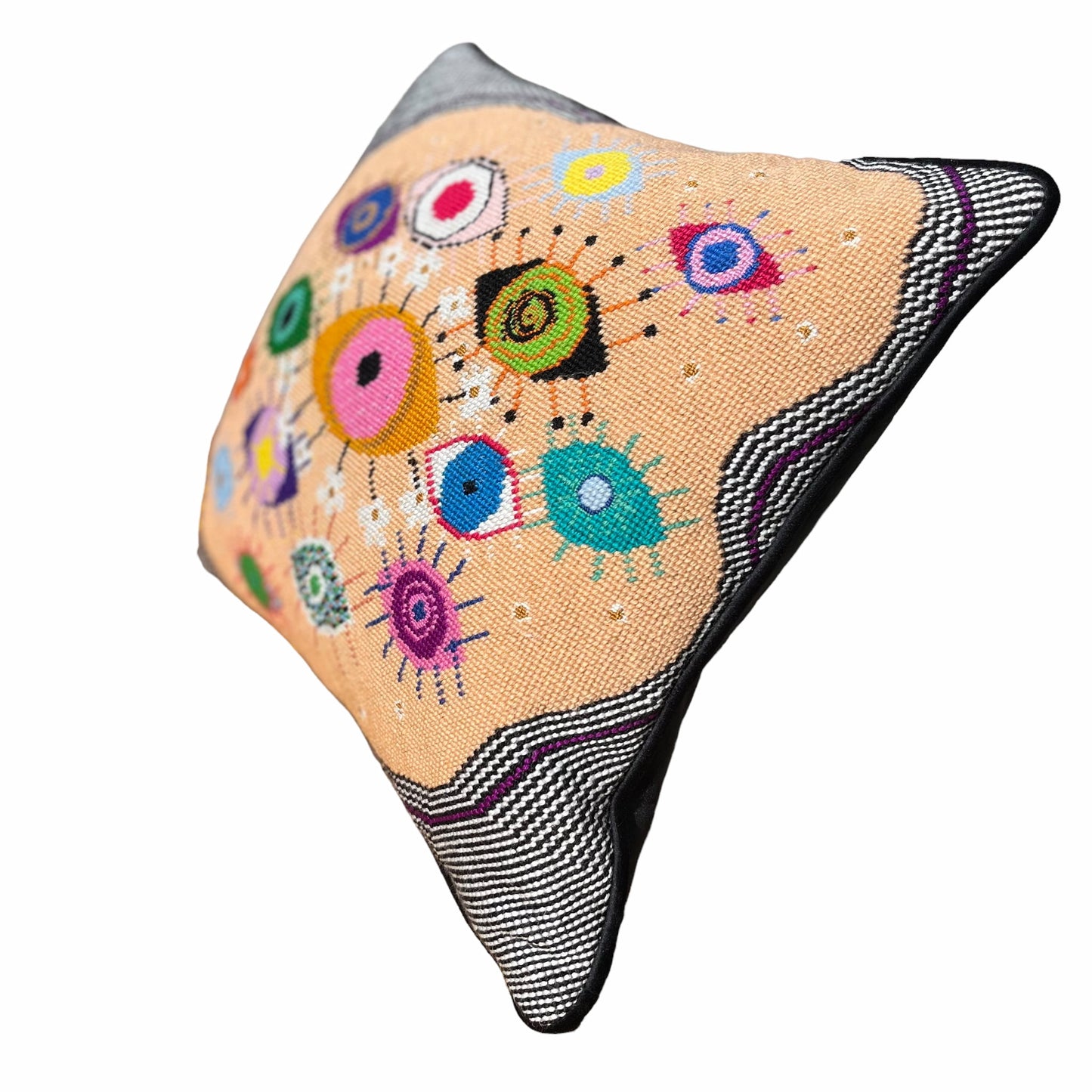 hand-embroidered lyrical pillow is covered in whimsical eyes of varying colors; vertigo band white swirl border