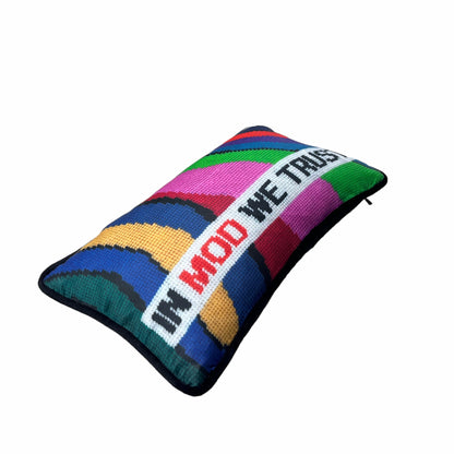 Pillow reads IN MOD WE TRUST across , with groovy , wavy color bands as background