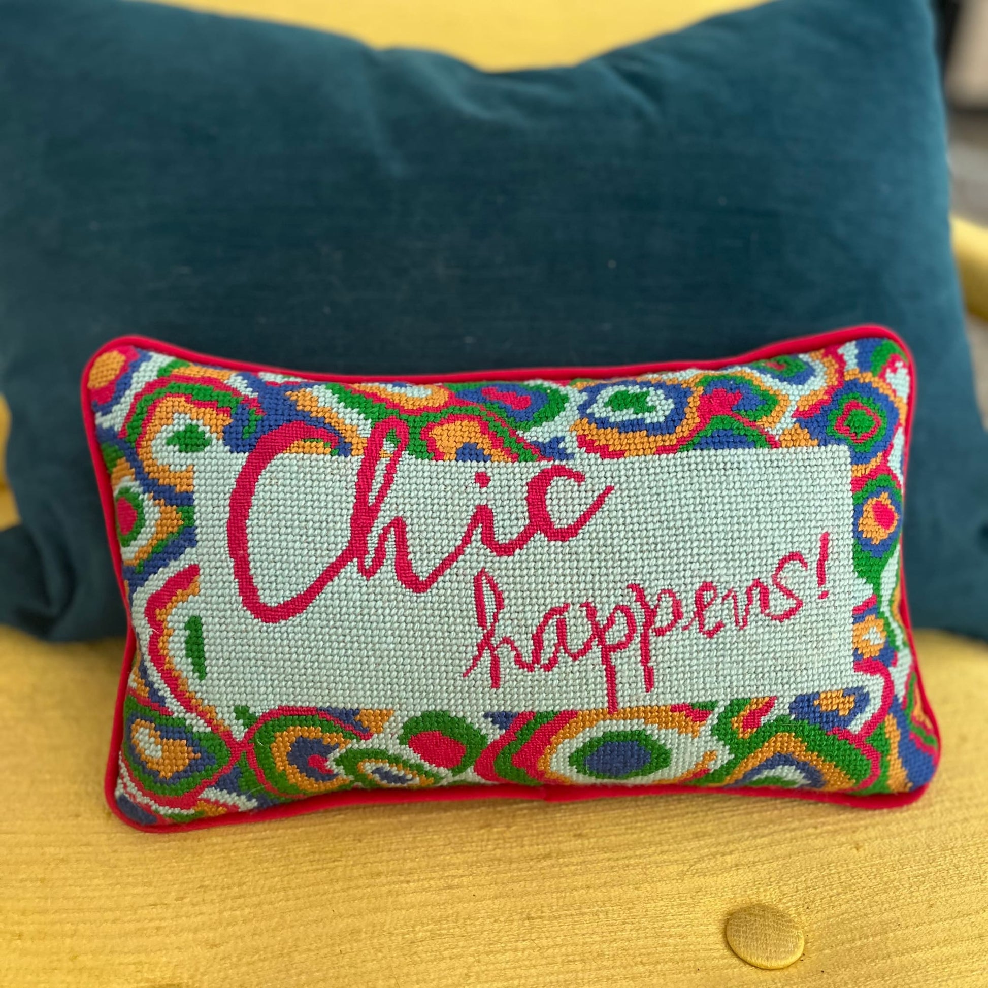 hand-embroidered needlepoint pillow features red, green, blue & gold paisley border with "Chic Happens!" written in red in the center