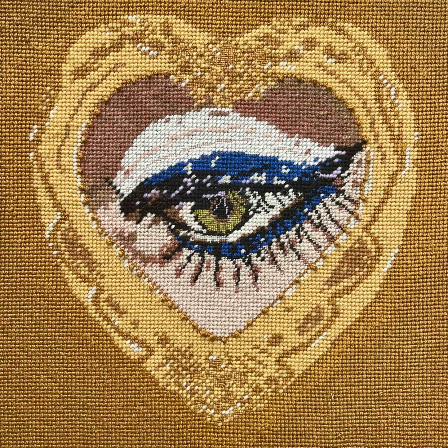 sultry green eye is framed in gold heart, hand-embroidered wool & silk pillow