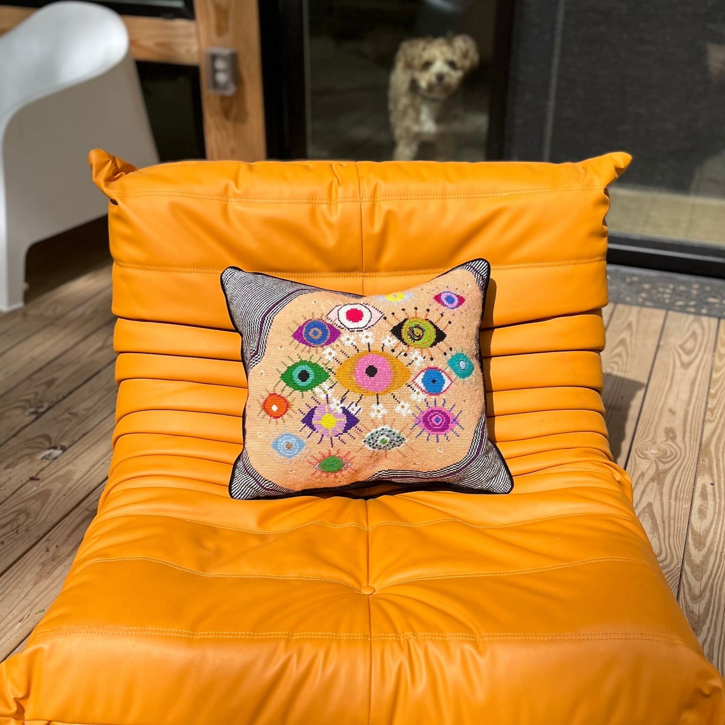 hand-embroidered lyrical pillow is covered in whimsical eyes of varying colors; vertigo band white swirl border