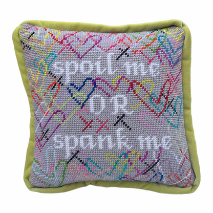 needlepoint SPOIL ME OR SPANK ME in white, surrounded by brightly colored hearts and a soft gray background