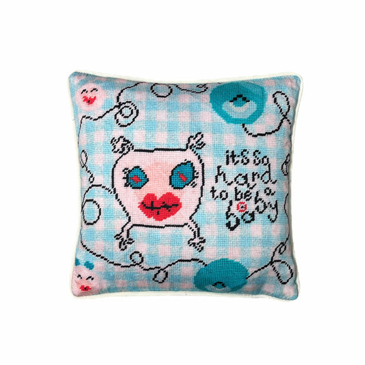 sweet monster pillow with big blue eyes & big red lips on baby blue checked background; says It's so hard to be a baby