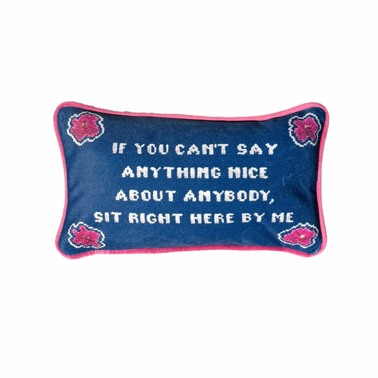 "If you can't say anything nice about anybody, sit right here by my" pillow with pink flowers in the corners and ink blue background.