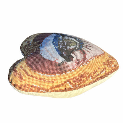 Mommani Threads x Haricot Vert "Heartfelt Glimpse" pillow is shaped like a heart and features a sultry green eye inside a gold frame.