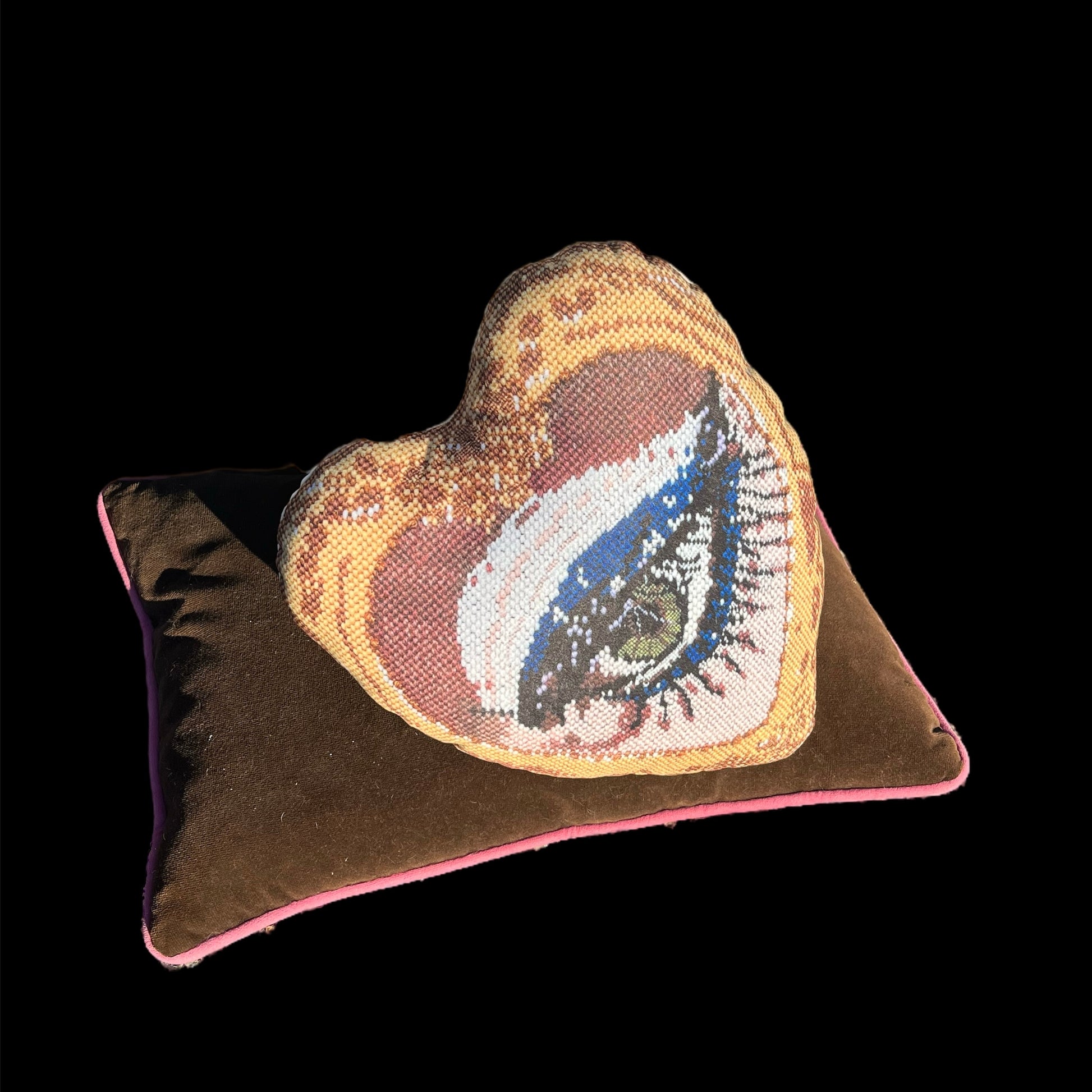 Mommani Threads x Haricot Vert "Heartfelt Glimpse" pillow is shaped like a heart and features a sultry green eye inside a gold frame.