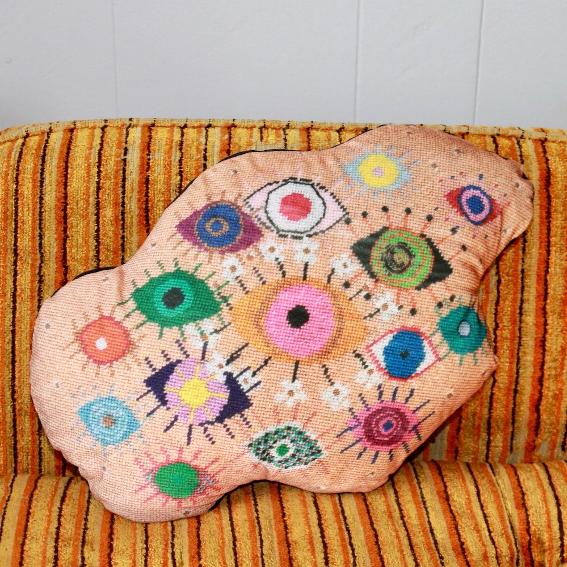 velvet amoeba-shaped pillow covered in fanciful, brightly-colored-eyes