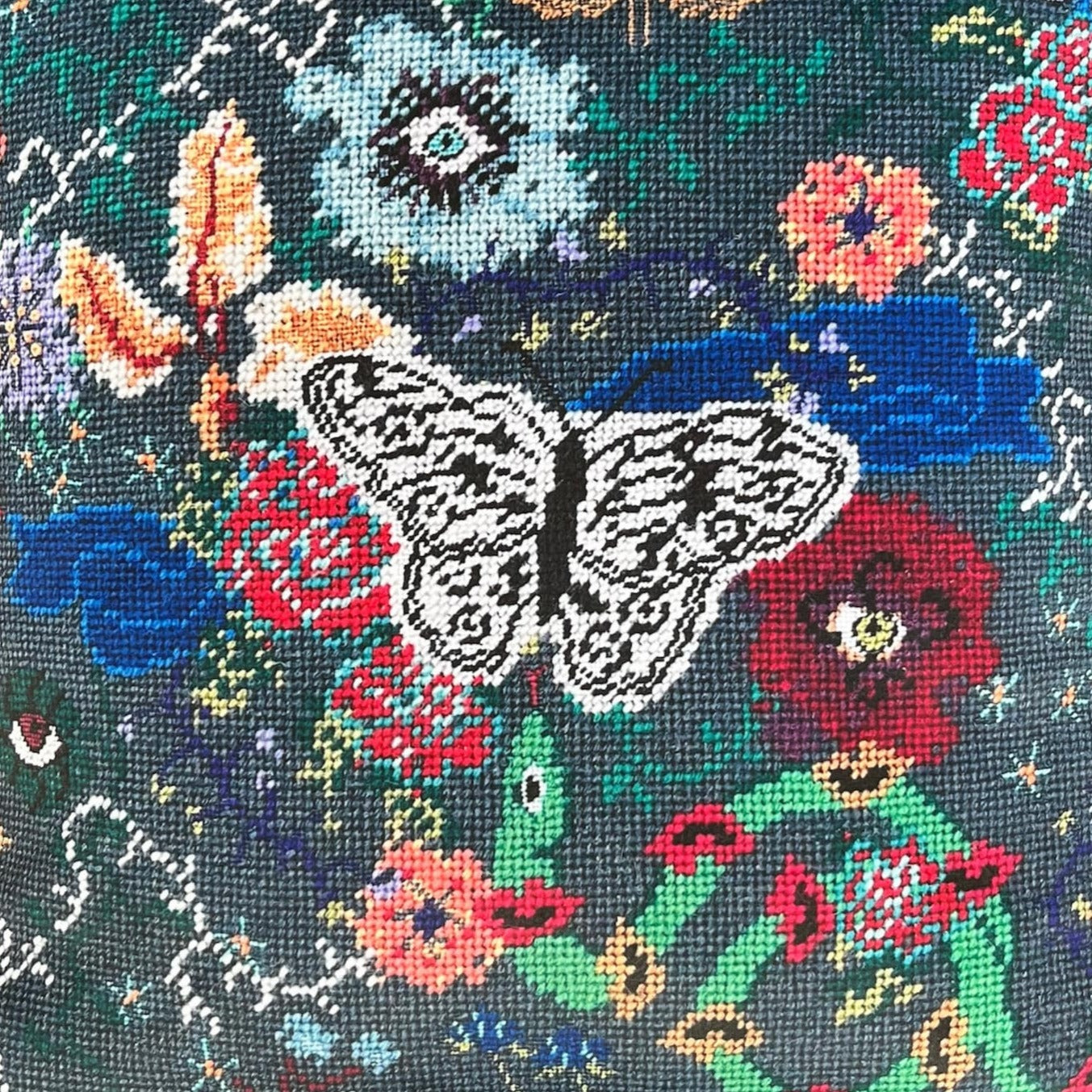 butterfly centers an array of surrealistic flowers with eyes; small flying creatures; snakes with lips, evoking a rich night-time feel