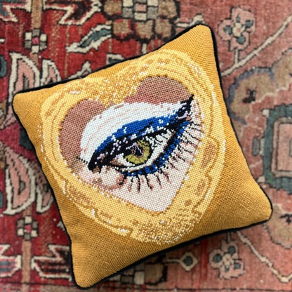 sultry green eye is framed in gold heart, hand-embroidered wool & silk pillow