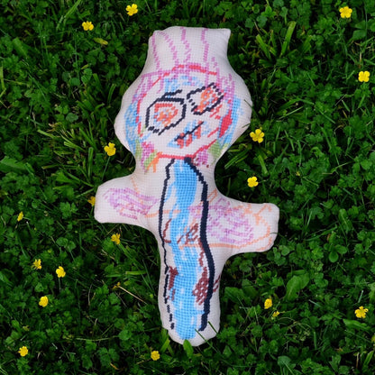 sculpted, colorful abstract monster with big eyes & wild hair laying on grass with yellow flowers