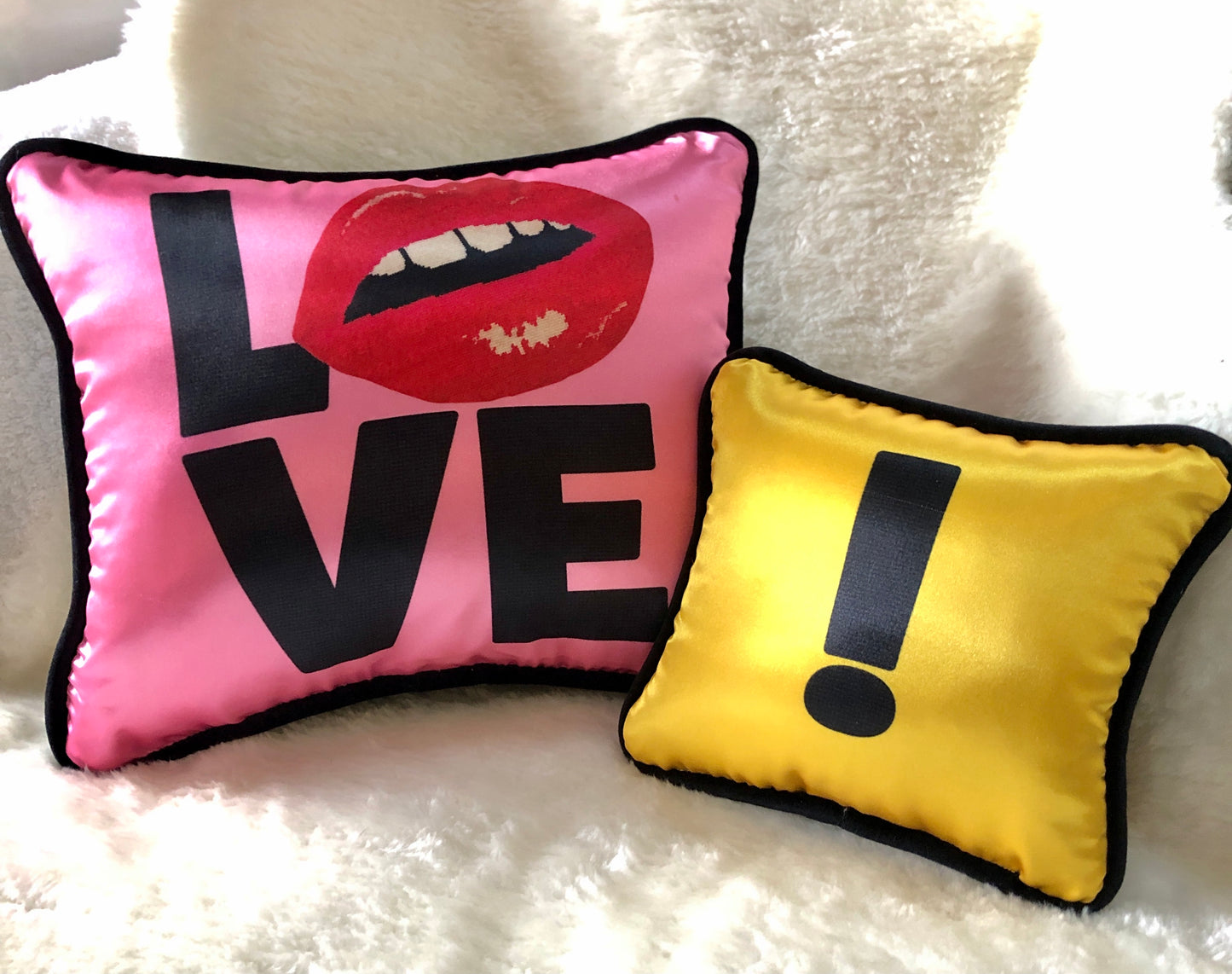 hot pink pillow with blackletters - L, red lips for an O, V & E stacked underneath with yellow pillow & black !