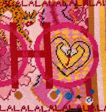 needlepoint pillow with pink and red colorful pattern, blue eye, cheetah, heart snakes, roses and lettering OOH in center with a LA LA LA border