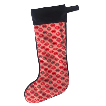 velvet holiday stocking covered in red lips with black cuff and hook, pink background