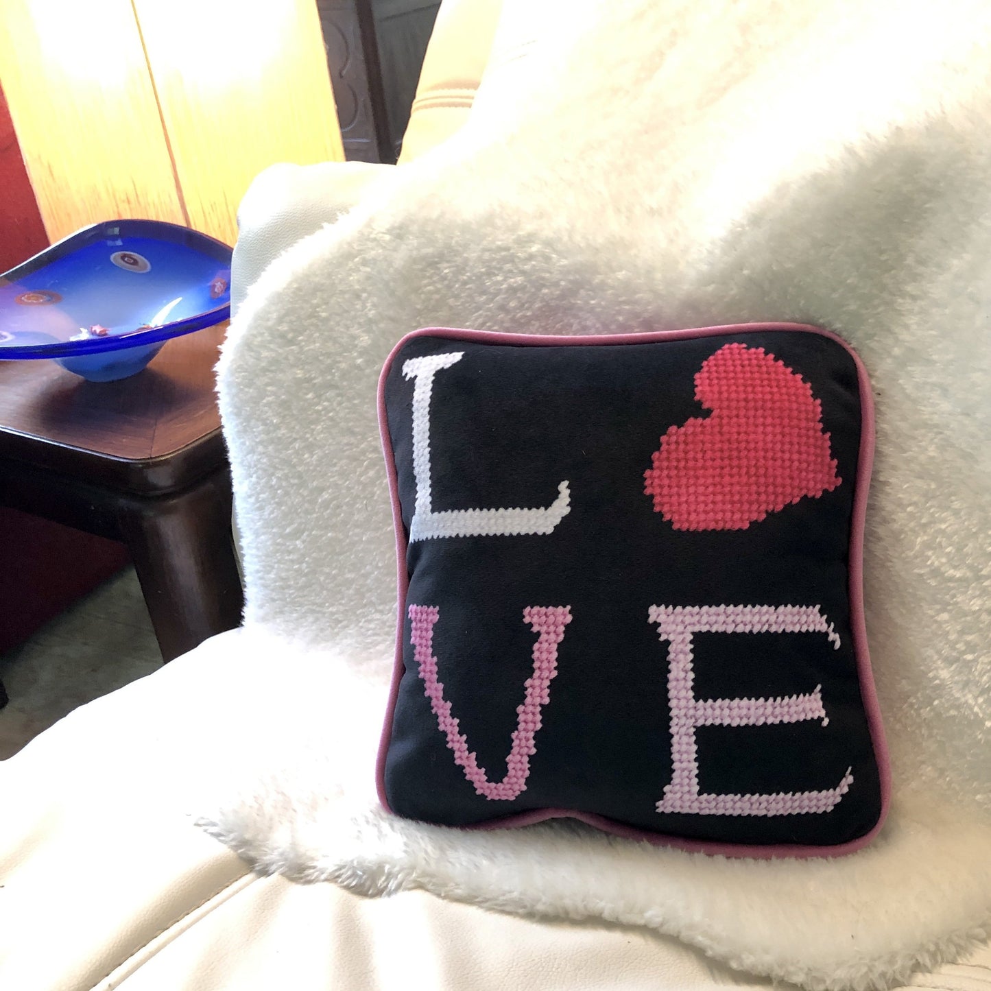 black velvet pillow with pink letters reading LOVE on a white leather lounge chair, murano dish