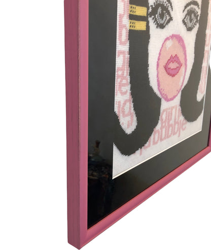 needlepoint big-eyed girl blowing pink bubble & hair flipped up, BUBBLE GIRL IN A BUBBLE GUM WORLD text behind image