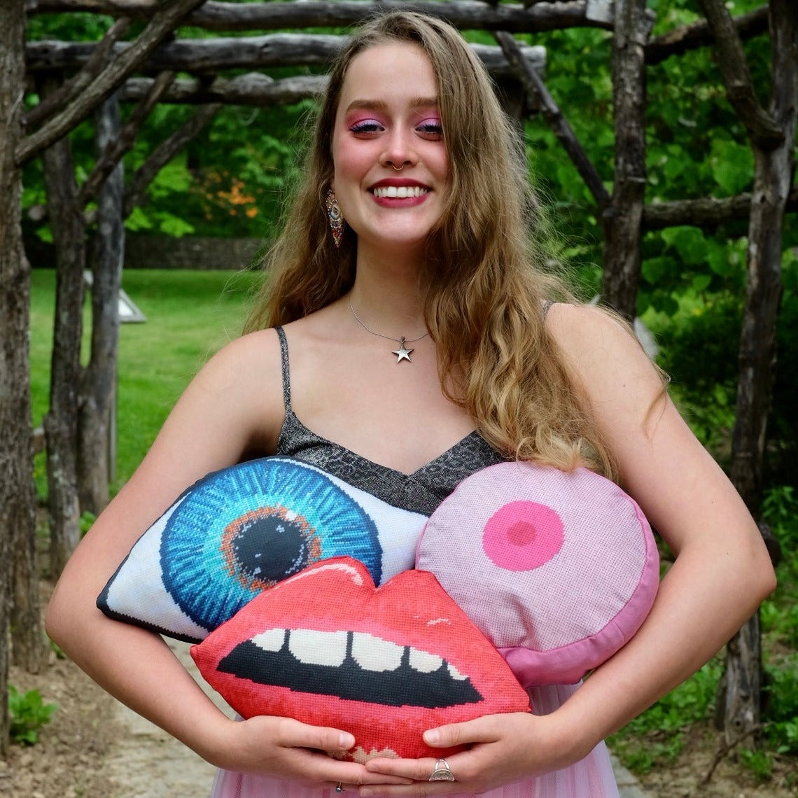 sculpted blue eye, pink boob and red lips pillow set, held by pretty blonde
