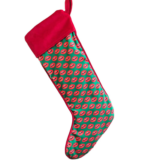 velvet holiday stocking covered in red lips with red cuff and hook, green background