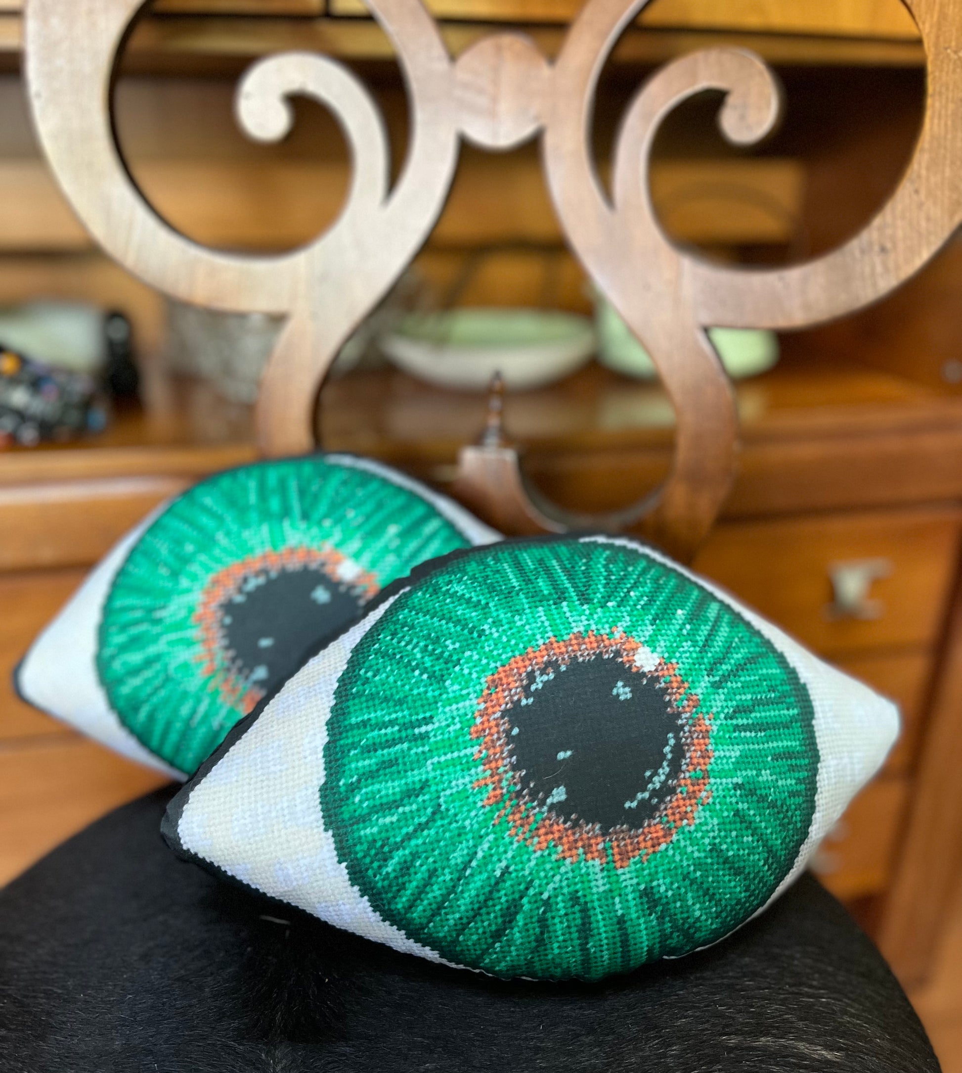 green eye sculpted pillow has gold at center, gradually turning to a dark green, on cowhide chair