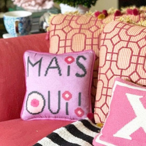 mais oui black stacked text with I dot and O that have cream colored centers with pink circles. Lavender pick background.