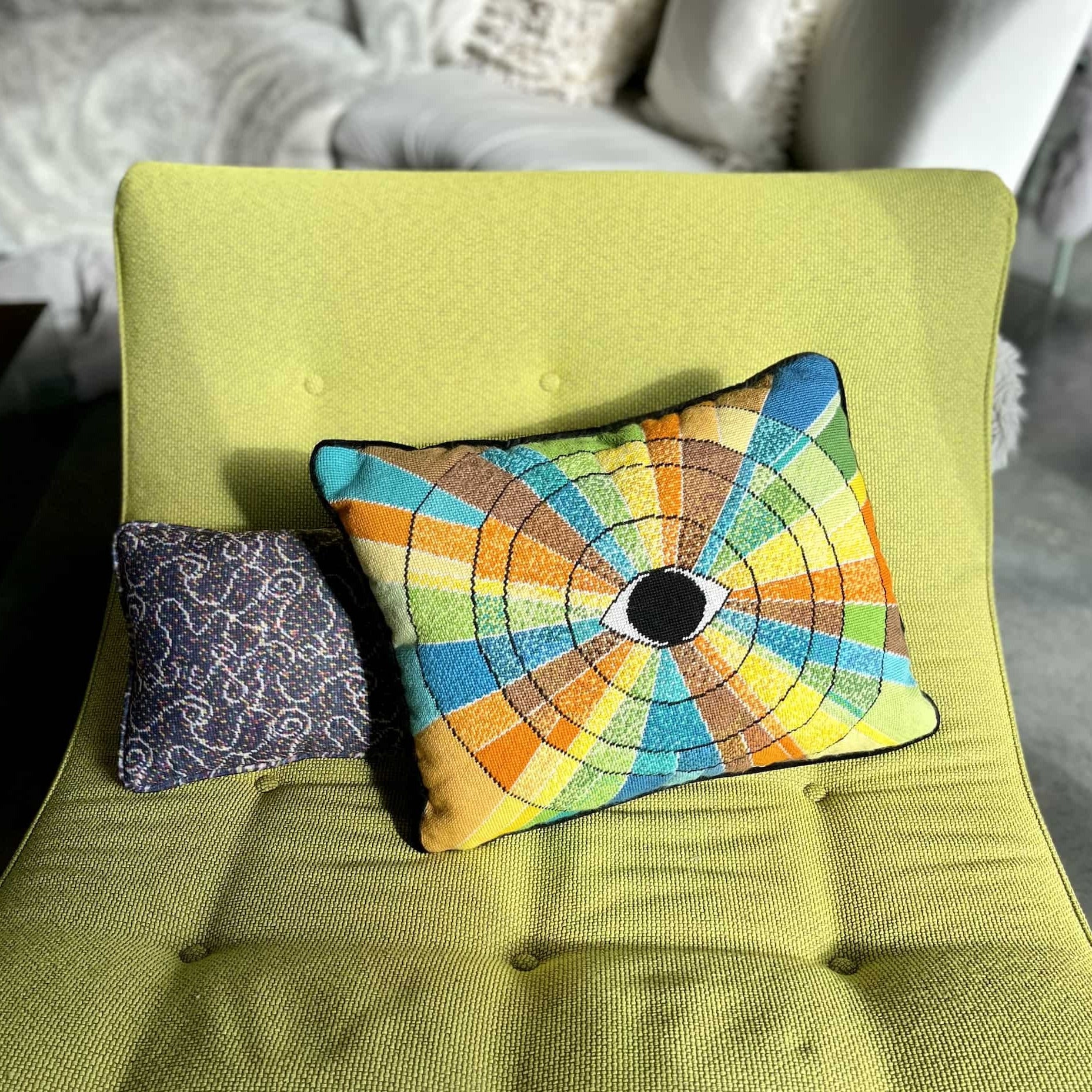 pillow has eye centered design with variegated rays of color - turquoise, green, brown, orange, yellow
