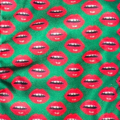 velvet holiday stocking covered in red lips with black cuff and hook, green background