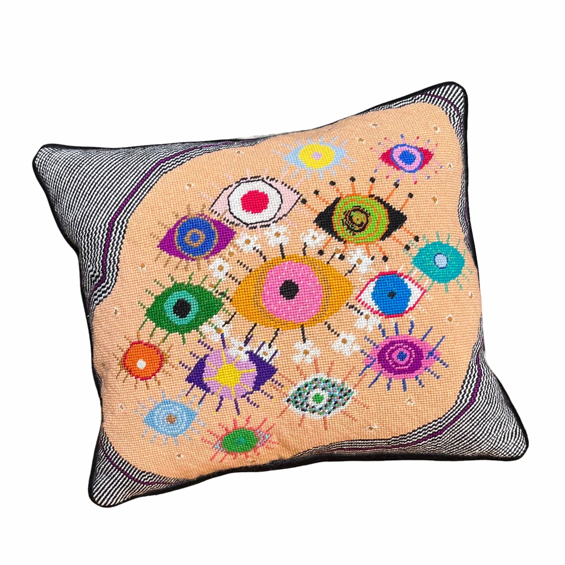 hand-embroidered lyrical pillow is covered in whimsical eyes of varying colors; vertigo band white swirl border