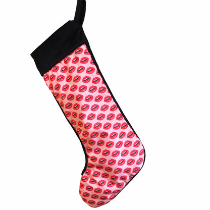 velvet holiday stocking covered in red lips with black cuff and hook, pink background