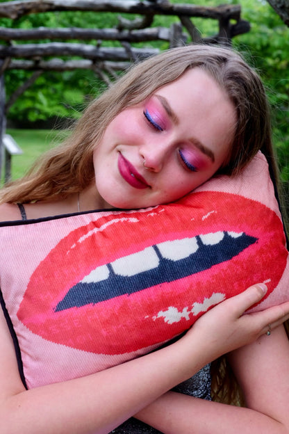 beautiful blonde model holds pink velvet pillow with red lips with open mouth and gapped teeth