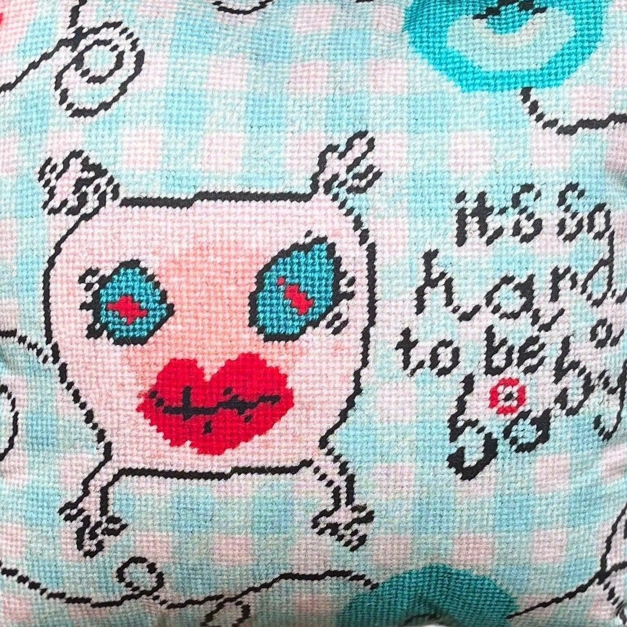 sweet monster pillow with big blue eyes & big red lips on baby blue checked background; says It's so hard to be a baby.