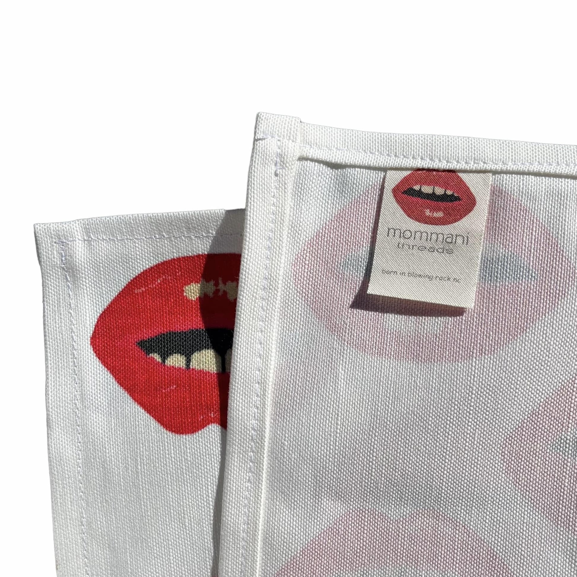 white tea towel covered  in rows of red lips scattered diagonally