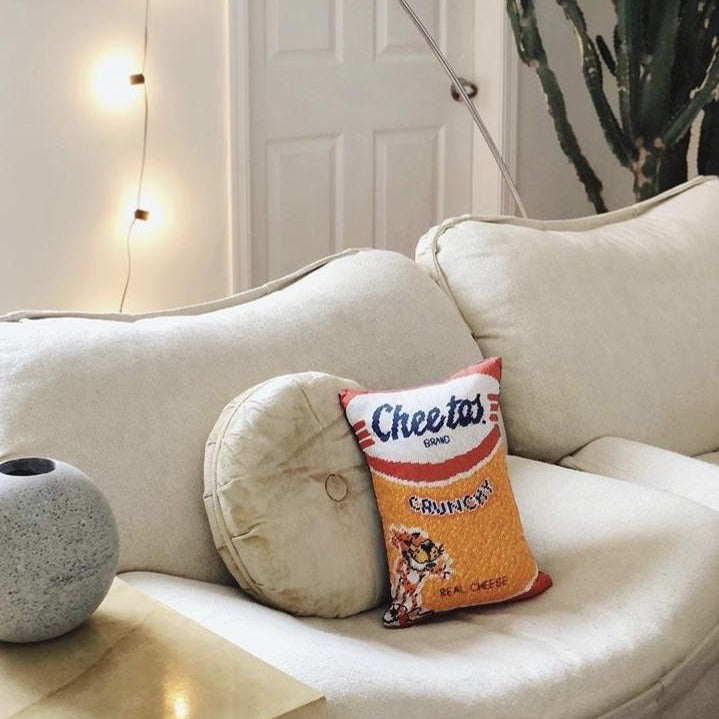 velvet Cheetos pillow with crunchy logo & Chester on modern couch