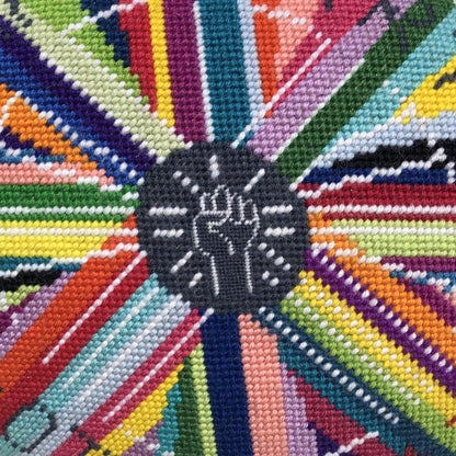 pillow center is dark gray with white fist pump, rainbow circle radiates out with GONNA START A REVOLUTION, cloud and stars border